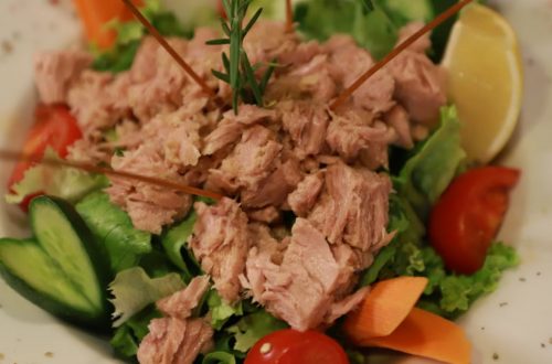 Close-up of a fresh tuna salad with vegetables and lemon garnish.