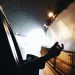A hand extends out of a car window while driving through a brightly lit tunnel.